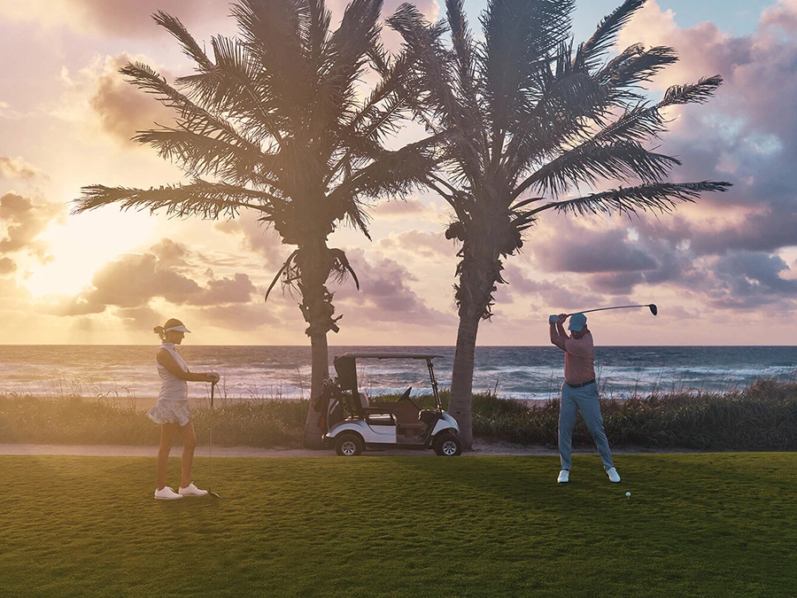 Golfers enjoying a round on a scenic oceanfront course in The Palm Beaches at sunrise.